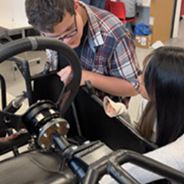 male teacher working on vehicle with female student